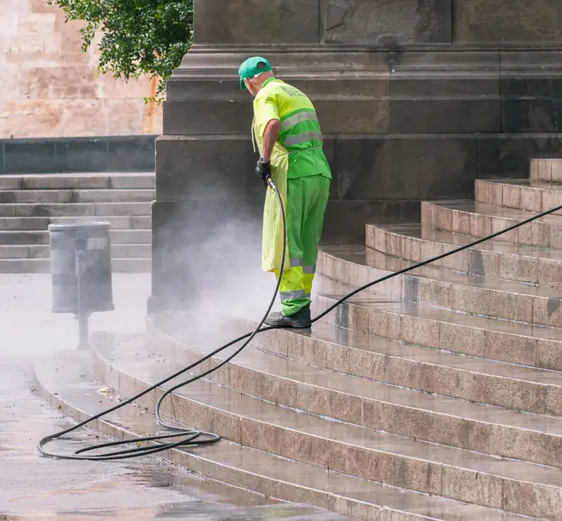 Person cleaning stone steps with a pressure washer